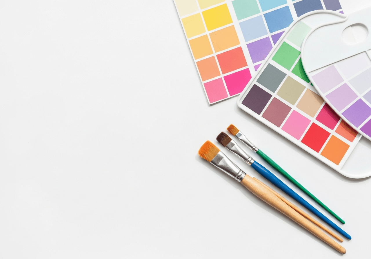 Flat lay of colorful artist paint brushes and vibrant paint palette swatches on a white background, representing creative tools for product photography